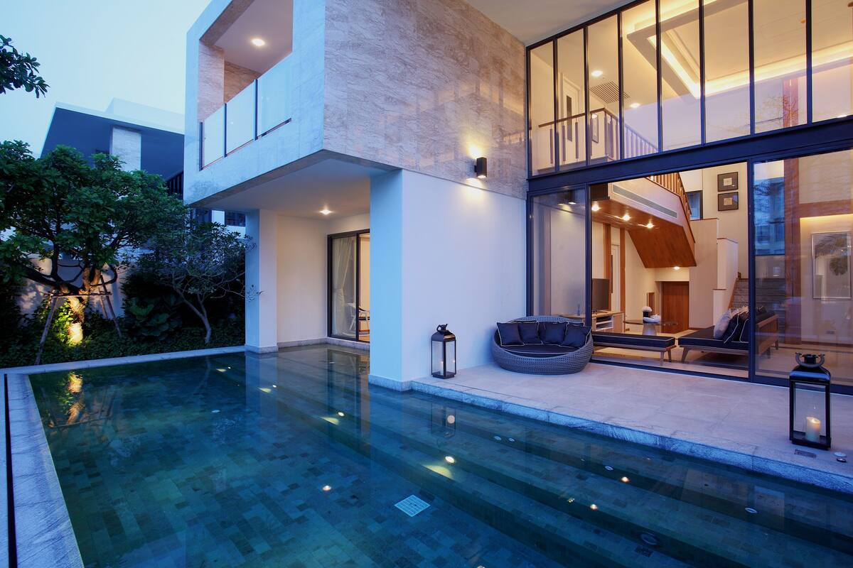 Une maison moderne dotée d’un patio entièrement vitré, d’une piscine et d’un coin salon confortable.