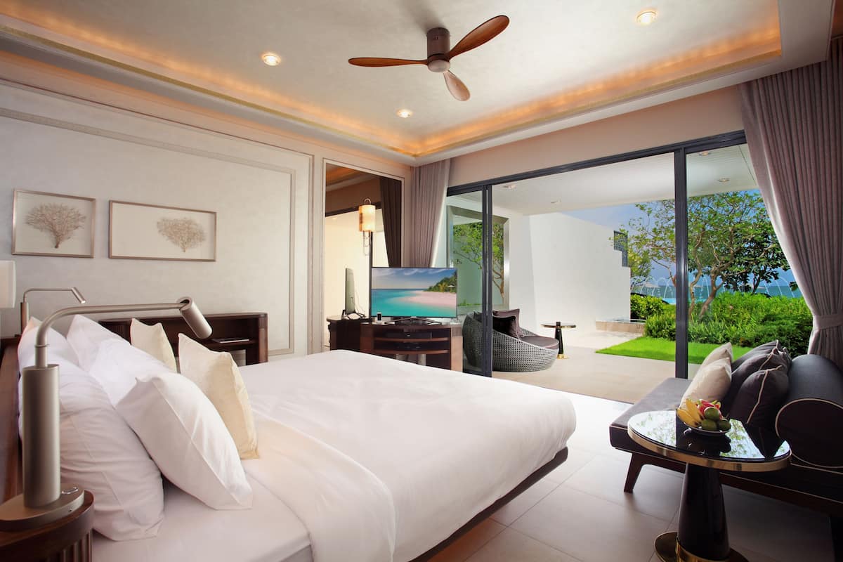 Une chambre d’hôtel moderne dotée d’un grand lit, d’une télévision à écran plat, d’un bureau et d’un balcon offrant une vue sur la mer.