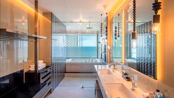 A modern bathroom with a large mirror, a sink, and a view of the sea.