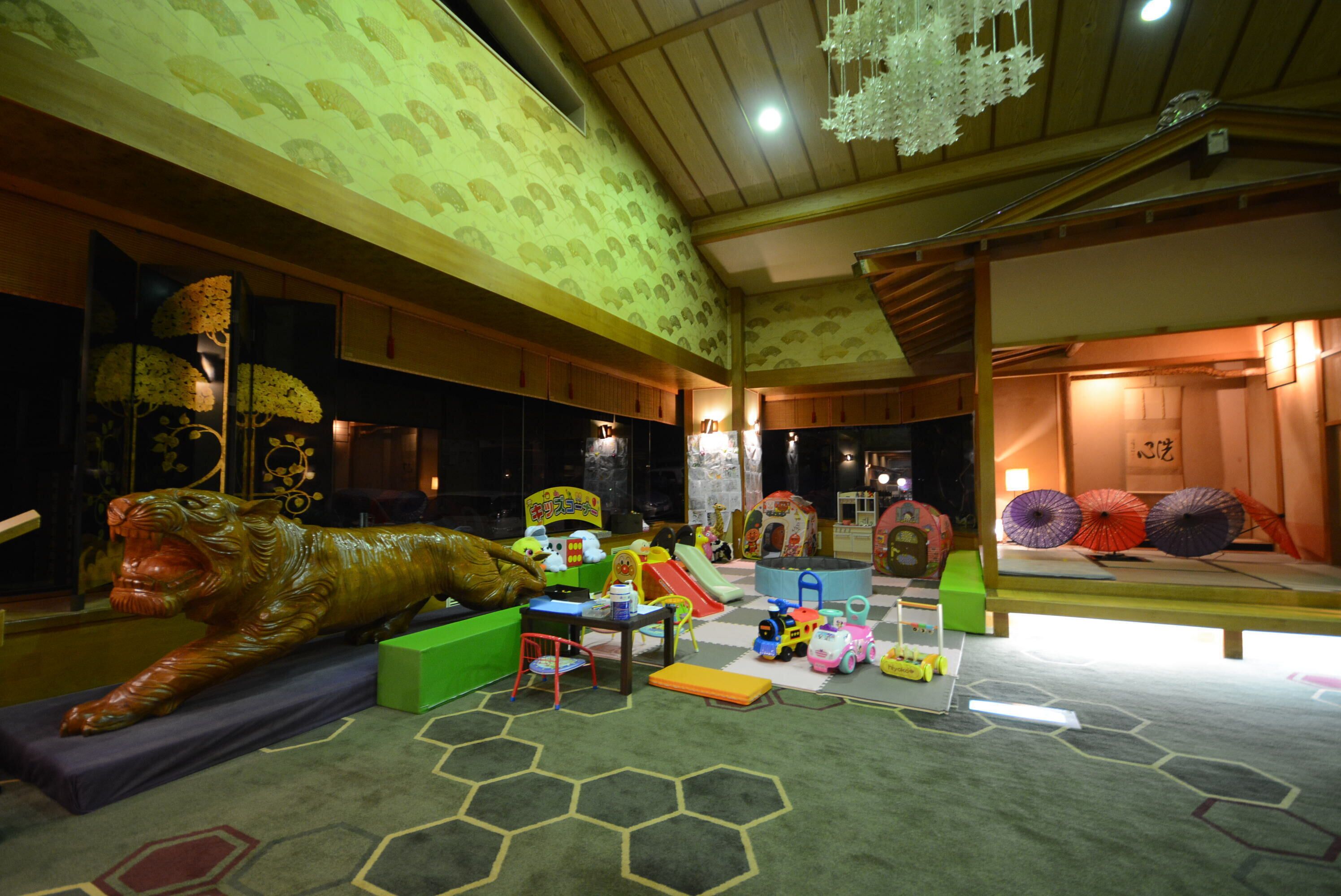 A playroom with a dinosaur sculpture, play structures, and colorful toys.