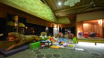 A playroom with a dinosaur sculpture, play structures, and colorful toys.