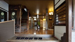 A hotel lobby with a wooden staircase, a shoe rack, and a traditional Japanese interior design. - Hinoderyokan (Ise)