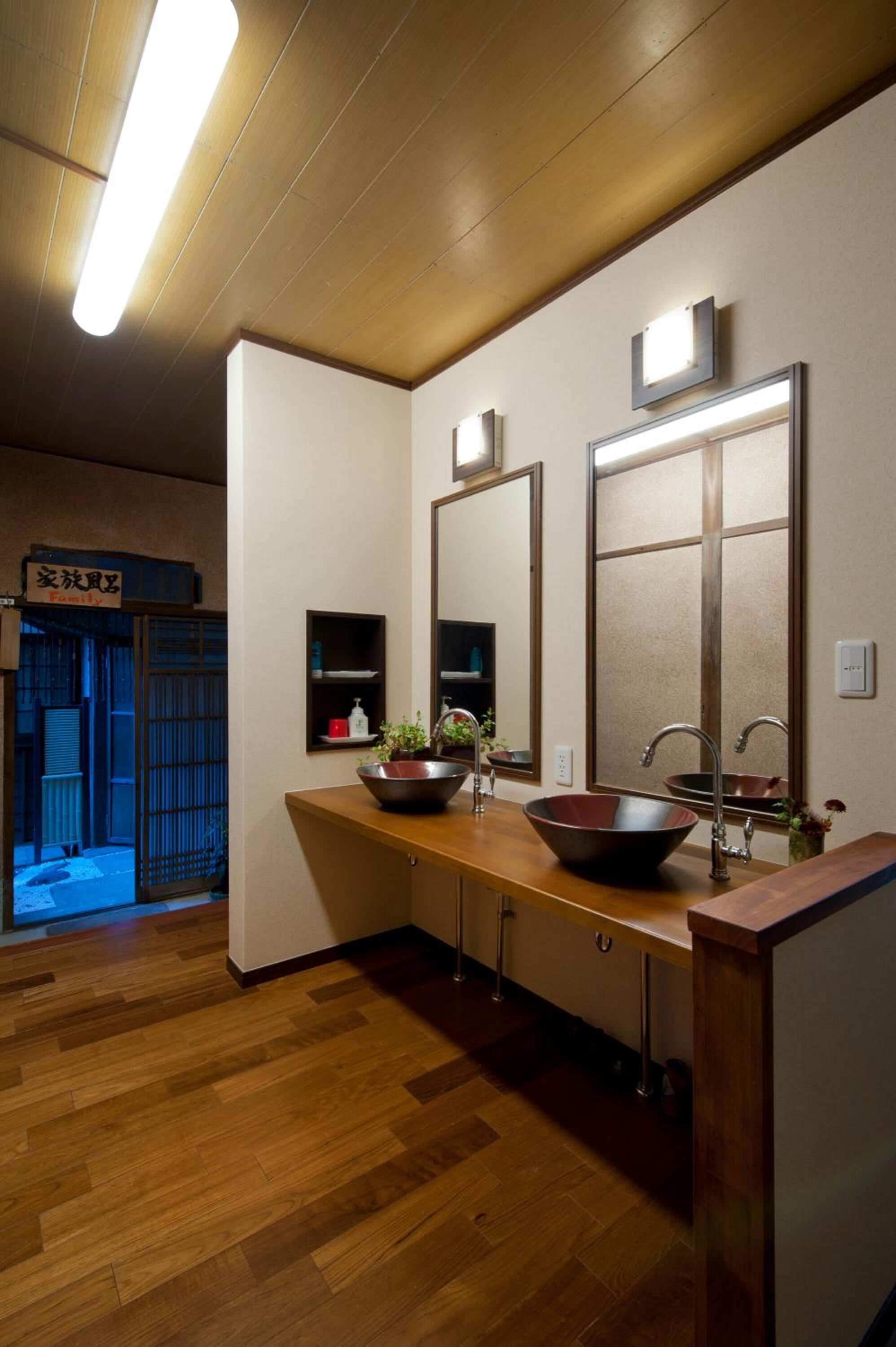 Un baño con piso de madera, dos lavamanos con espejos grandes y un mueble de tocador de madera.