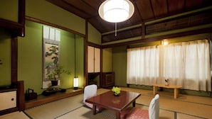 A traditional Japanese room with tatami flooring, a low wooden table, a sofa, and a sliding door. - Hinoderyokan (Ise)