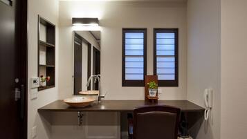 A modern bathroom with a large mirror, two windows, a sink, and a chair.