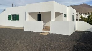 Un bâtiment blanc avec une seule porte et une fenêtre dotée de volets verts.