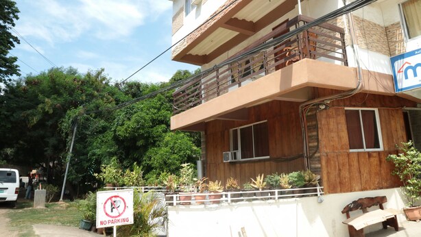 A two-story building with a balcony, a 'No Parking' sign, and a 'Mandaufoam' sign indicating a furniture center. - Centillo Travellers Inn (Malay)