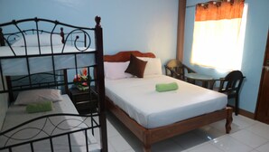 A room with a bunk bed, a single bed, a nightstand with a lamp, and a window with curtains. - Centillo Travellers Inn (Malay)