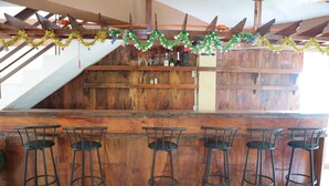 A bar area with wooden bar counter and metal stools. - Centillo Travellers Inn (Malay)