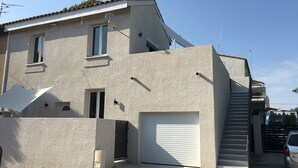 Ein zweigeschossiges Haus mit Garage, Satellitenschüssel und einem kleinen Balkon.