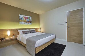 A modern bedroom with a large bed, bedside tables, a wooden door, and a wall-mounted abstract art piece. - Portico Residence (Bangkok)