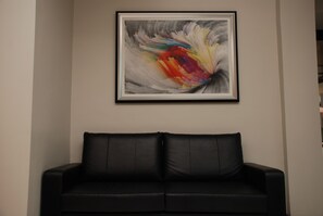 Eine schwarze Ledersofa in einem Raum mit einem gerahmten abstrakten Gemälde an der Wand.