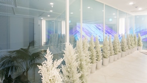 A modern interior with a row of artificial trees, large windows, and a ceiling with recessed lighting. - H Avenue Hotel Idae Shinchon (Seoul)