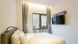 A hotel room with a bed, a TV mounted on the wall, and a window with curtains. - H Avenue Hotel Idae Shinchon (Seoul)