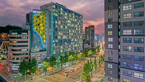A modern hotel with multiple floors, large windows, and a distinctive yellow and blue facade. - H Avenue Hotel Idae Shinchon (Seoul)