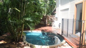A swimming pool surrounded by stone tiles, with a wooden deck and a metal fence. - Beach House on Fox (Cable Beach)