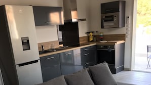 Et moderne køkken med en grå sofa, vanddispenser, mikroovn og komfur.