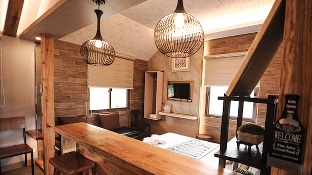 Una zona con barra de madera, un letrero que dice 'Welcome', un televisor y una escalera.