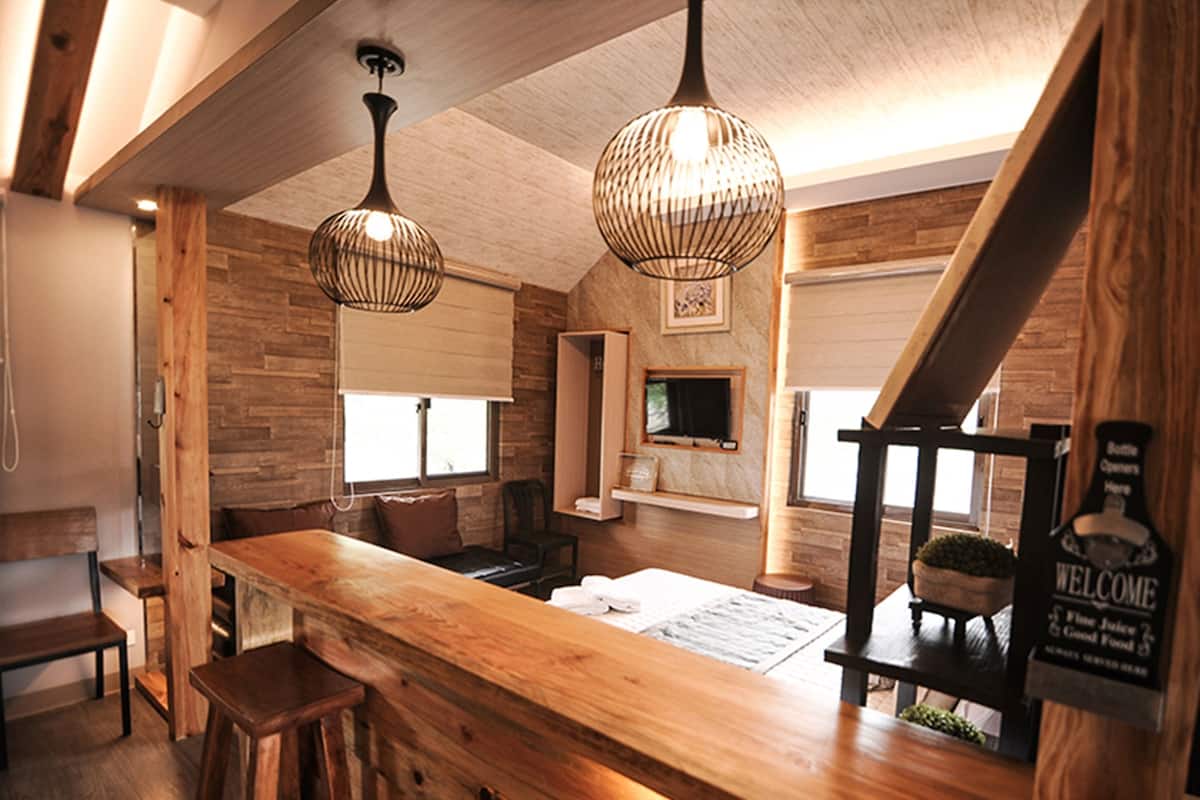 A wooden bar area with a 'Welcome' sign, a television, and a staircase.