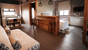 Amplia sala de estar con una mesa de comedor de madera, un sofá y una cocina con salpicadero de piedra.