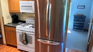 A kitchen with wooden cabinets, a stainless steel refrigerator, a stove, and a microwave.