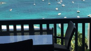 A balcony with a table and chairs overlooking a turquoise sea with several boats. -   Spacious 3 Bed 3 Full Baths With Spectacular Views of St John- Ocean Front!
 (Saint Thomas)
