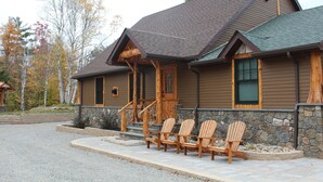 A lodge with a stone foundation, wooden exterior, and a covered porch with Adirondack chairs.