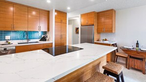 Eine moderne Küche mit Holzschränken, einem Edelstahlkühlschrank und einer Marmorarbeitsplatte.