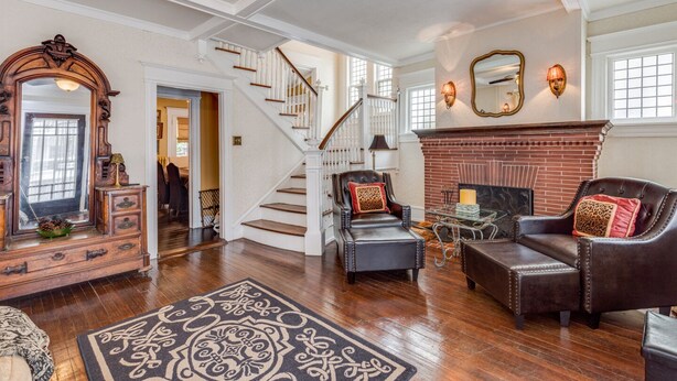 A spacious living room with a fireplace, a staircase, and a large mirror. - Victorian Home - Golfers Welcome (Ventnor)