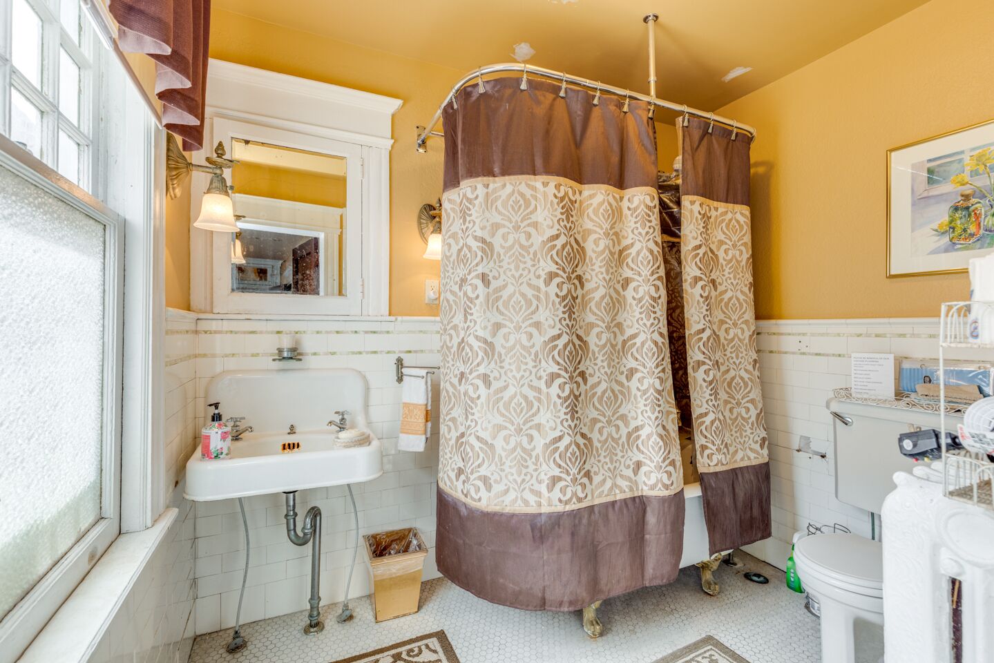 A bathroom with a white sink, a mirror, a shower curtain, and a toilet.