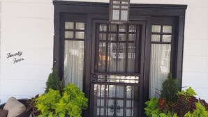 A dark wooden entrance with a glass door, a hanging lantern, and potted plants on either side. - Victorian Home - Golfers Welcome (Ventnor)