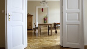 A dining area with a wooden table and chairs, a chandelier, and a cabinet in the background.