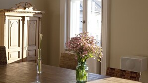 A dining table with a vase of flowers and a tall vase with a single flower.