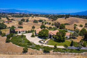 A residential area with houses featuring Mediterranean architecture, surrounded by green lawns and trees. - Hidden Views Mission Style  house on 10 acres (Solvang)