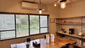 A dining area with a wooden table, chairs, a potted plant, and a 'cafe lounge' sign. - Yakushima Guesthouse Suginoko (Yakushima)
