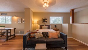 A cozy bedroom with a bed, a dark sofa, a small table, and a ceiling fan. - Gorgeous Casita In The Heart Of Historic Old Town  (Albuquerque)