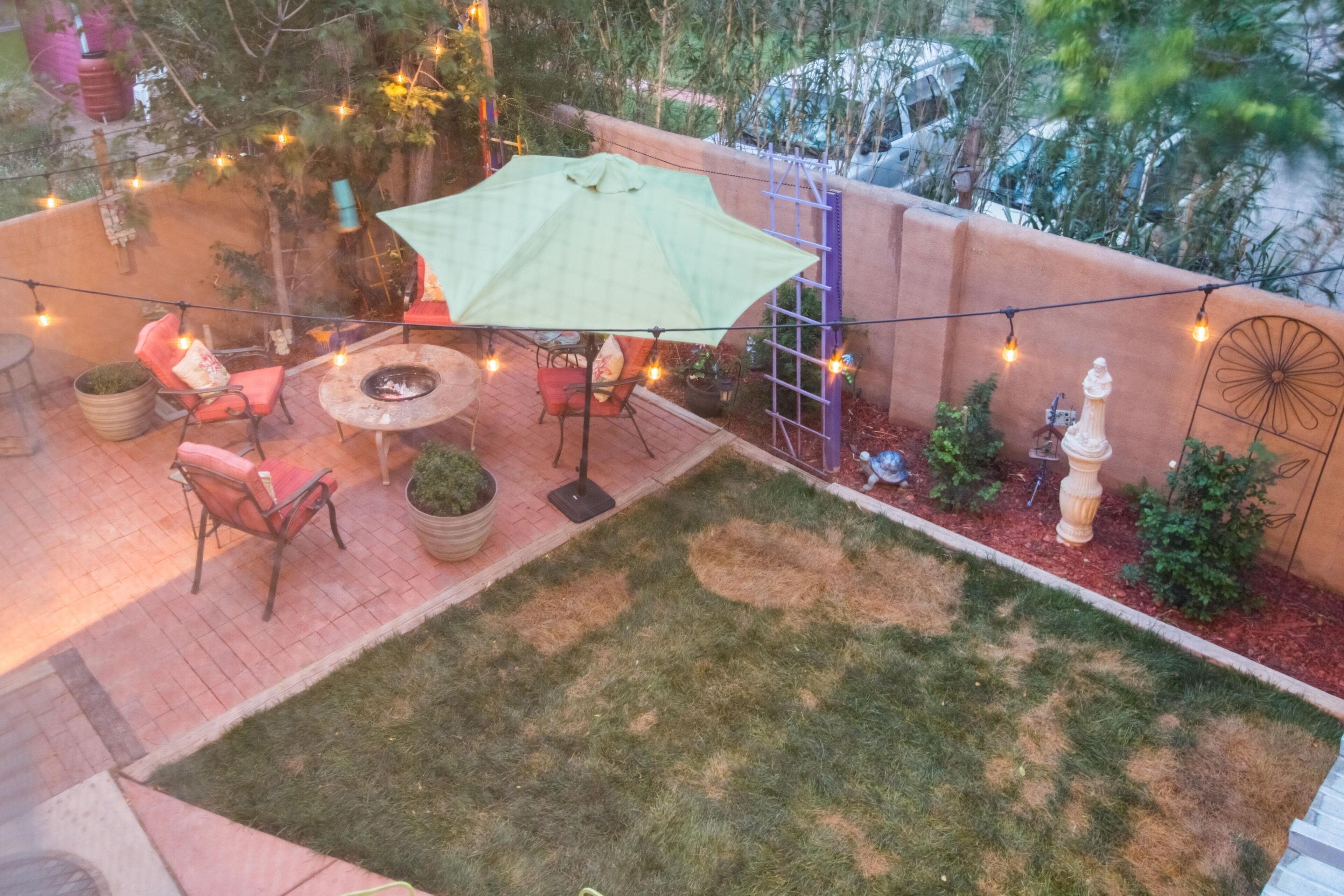 A patio with a fire pit, outdoor furniture, and string lights.