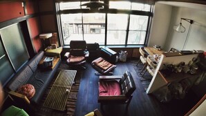 A cozy living room with a curved ceiling, a sofa, a chair, and a small table. - YAWP! backpackers - Hostel (Tokyo)