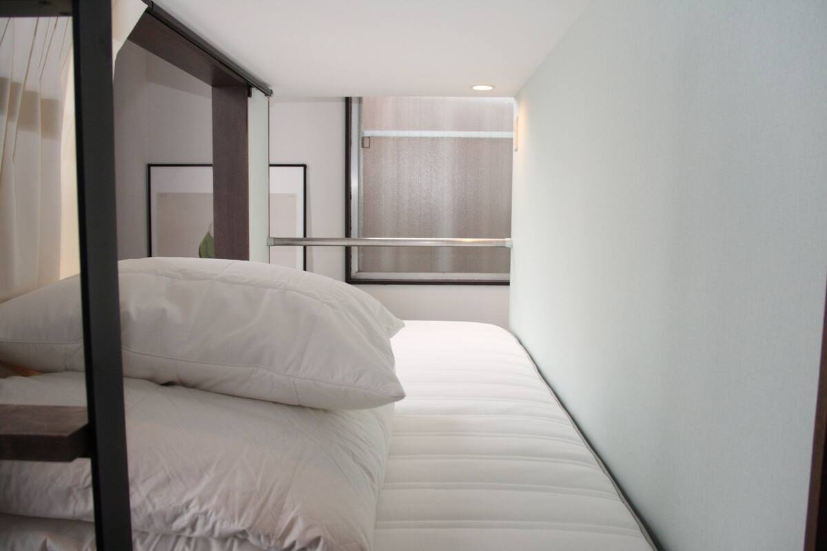 Una habitación de hotel moderna con una cama, un ventanal y un espejo.