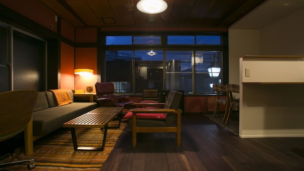 A cozy living room with a sofa, chairs, a coffee table, and a large window with a view of the outside. - YAWP! backpackers - Hostel (Tokyo)