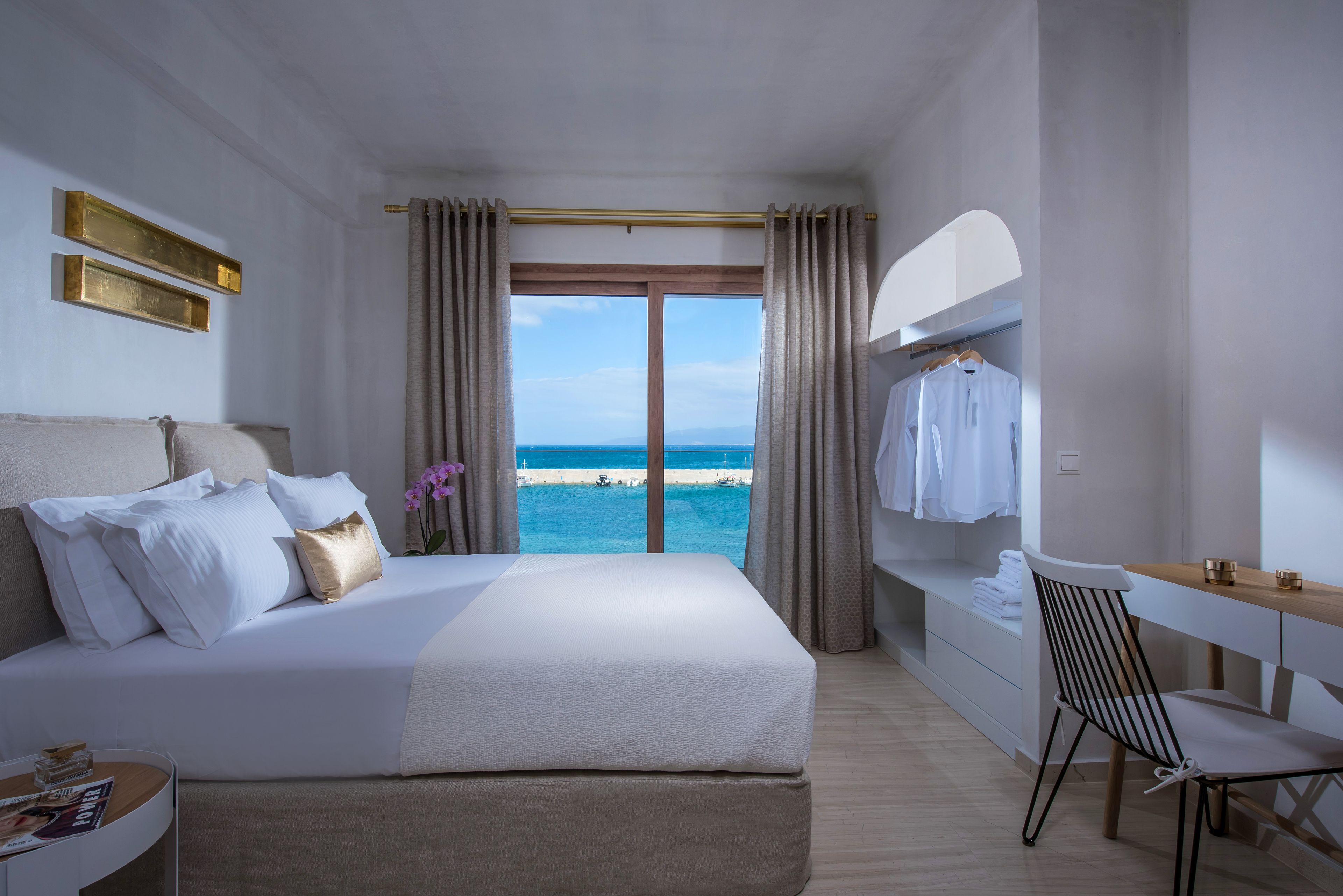 Ein Hotelzimmer mit einem großen Bett, einem Schreibtisch und Blick auf den Strand.
