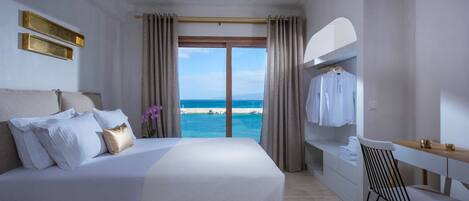 Ein Hotelzimmer mit einem großen Bett, einem Schreibtisch und Blick auf den Strand.