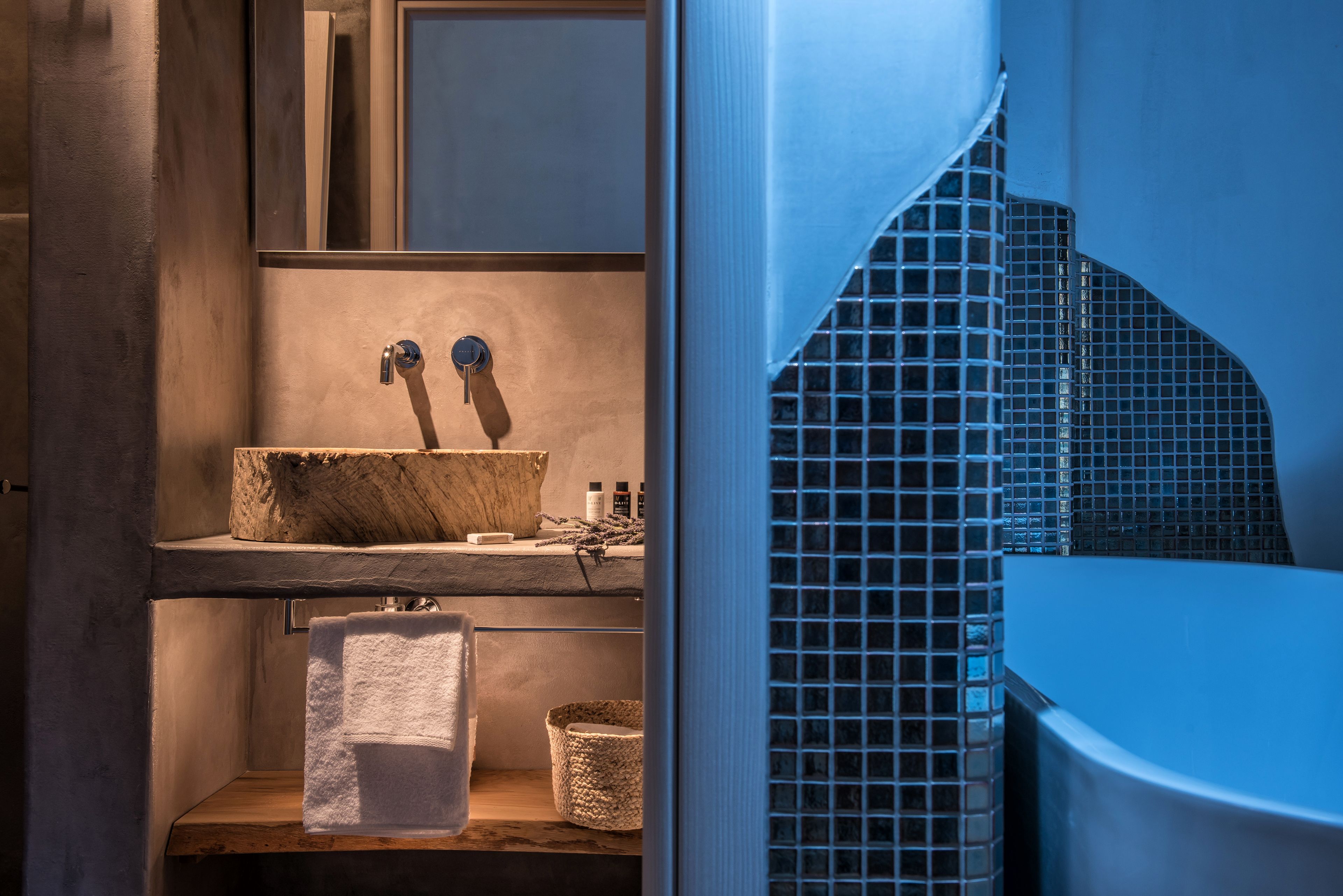 A bathroom with a wooden vanity, a sink with two faucets, a towel rack, and a tiled shower area.