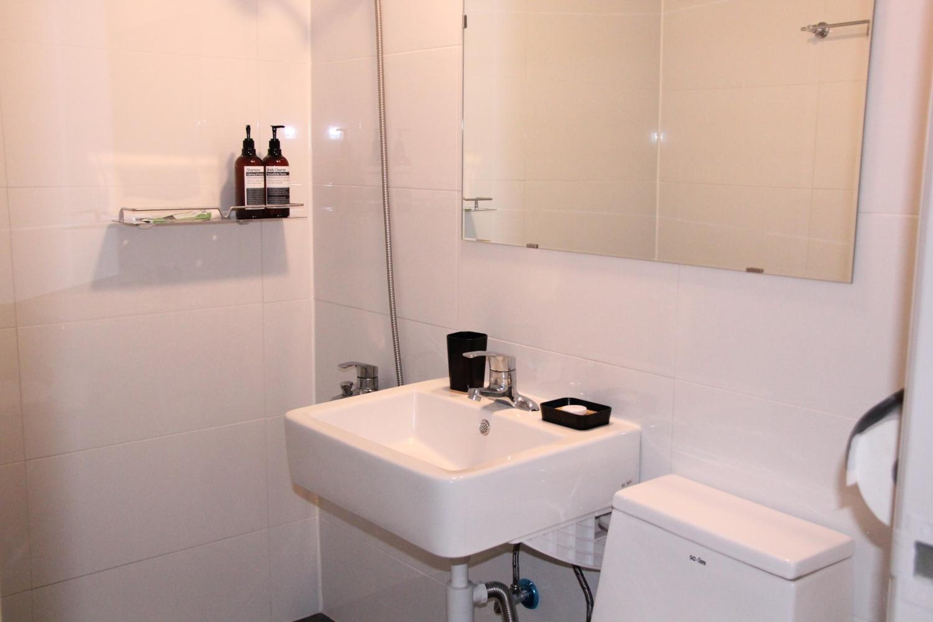 Un baño con lavamanos blanco, un espejo, inodoro y ducha.