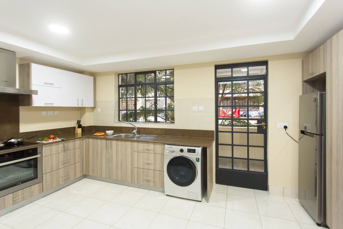 Una cocina moderna con lavadora integrada, un refrigerador y una ventana con vistas al exterior.