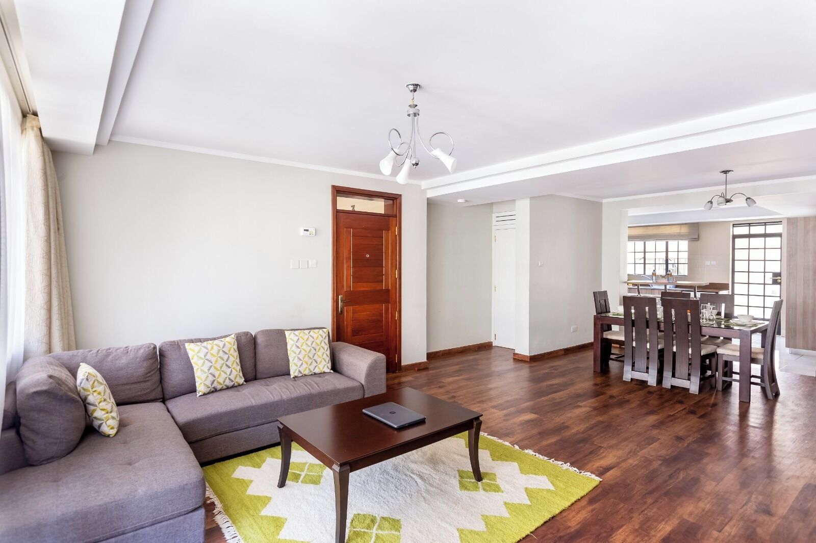 A living room with a sofa, coffee table, and dining area with chairs and a table.