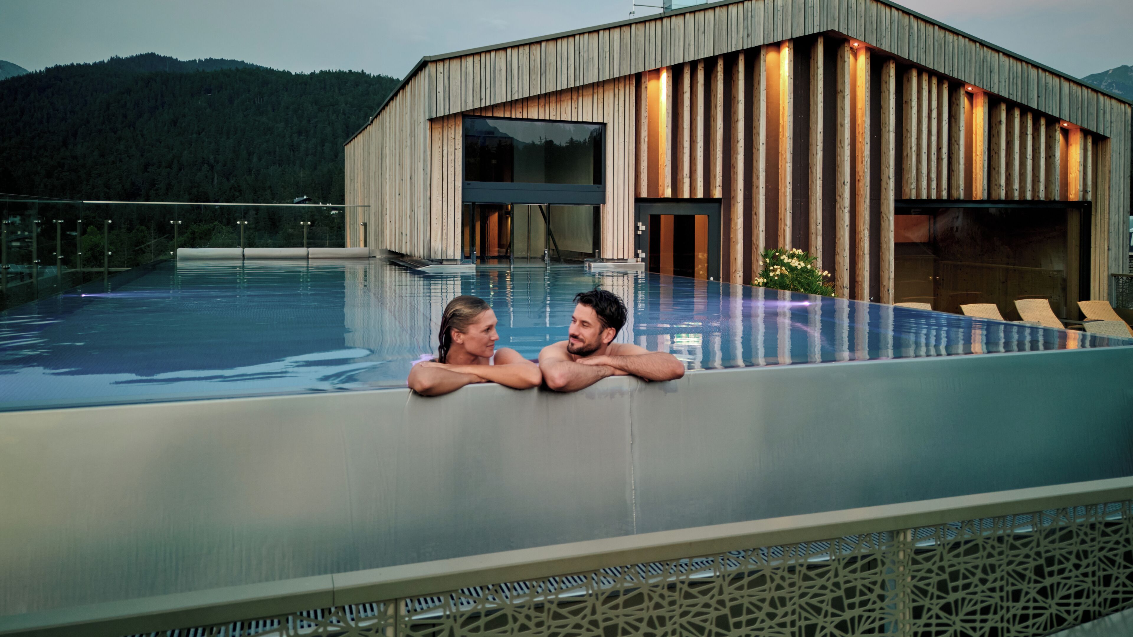 A modern building with a wooden facade and a glass infinity pool.