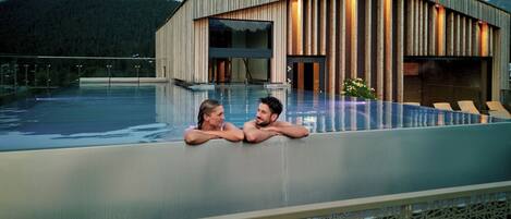A modern building with a wooden facade and a glass infinity pool.