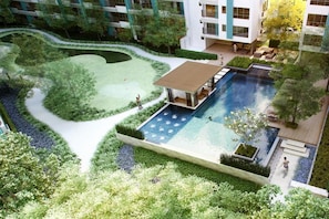 Un edificio moderno con piscina, rodeado de jardines ajardinados y senderos.