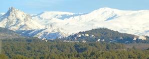 Een bergachtig landschap met besneeuwde toppen en een dorpje verscholen tussen de heuvels.